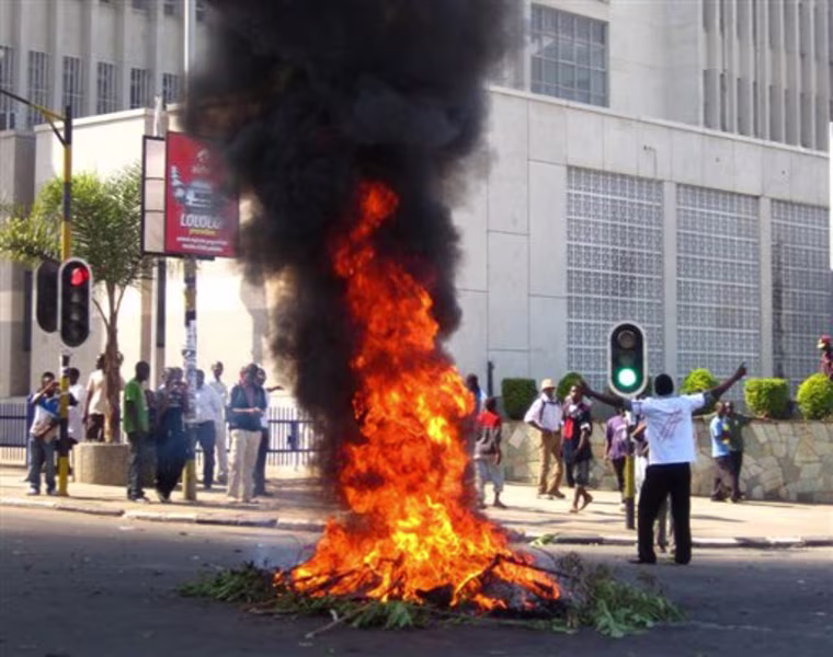 A protester burns vegetation in a street in Lilongwe, Malawi, Wednesday, July 20, 2011. Protesters went on the rampage after a court injunction stopped them protesting the economic and democratic crisis in the country. A coalition of more than 80 rights groups had organised nationwide protest marches for Wednesday. They wanted to protest what they say are moves by the Malawi's President Bingu wa Mutharika to roll back hard-fought democratic gains made since the first democratic polls in 1994 removed dictator Kamuzu Banda from power. (AP Photo/Diane Boles)